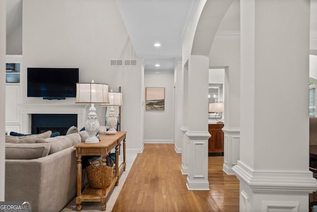 living room featuring visible vents, arched walkways, a fireplace, light wood-type flooring, and recessed lighting