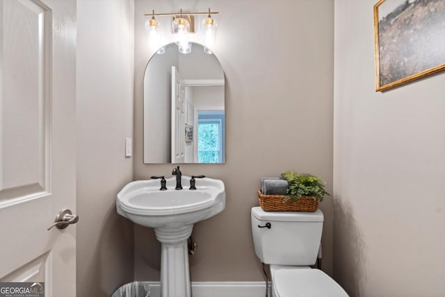 half bath featuring baseboards and toilet