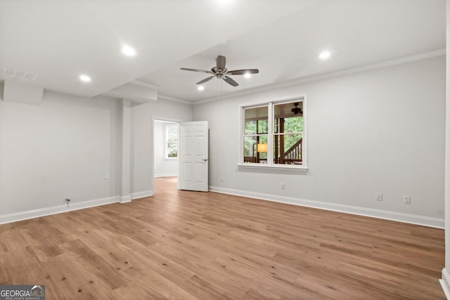 empty room with ceiling fan, visible vents, baseboards, light wood finished floors, and ornamental molding