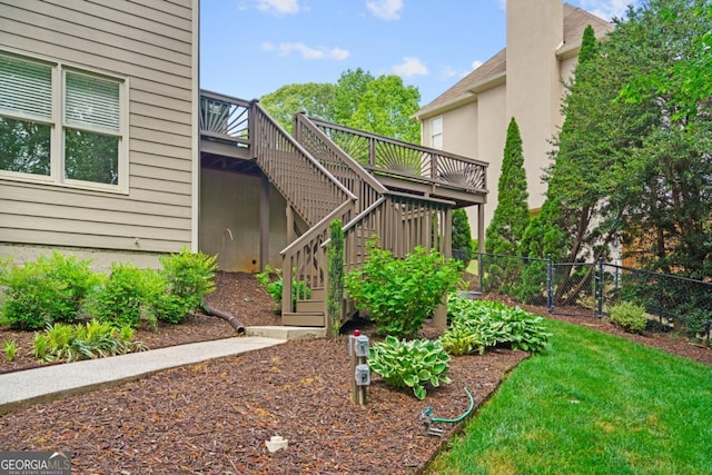 view of yard featuring a deck, fence, and stairs