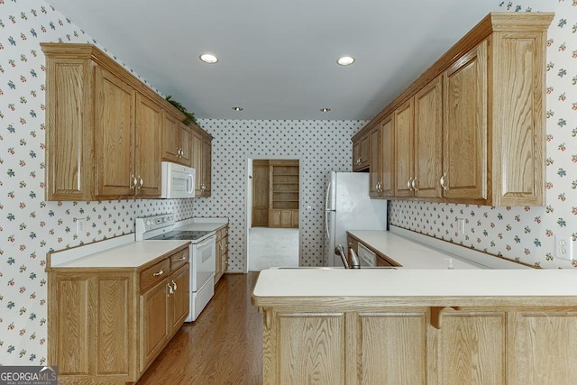 kitchen featuring white appliances, wallpapered walls, wood finished floors, light countertops, and a peninsula