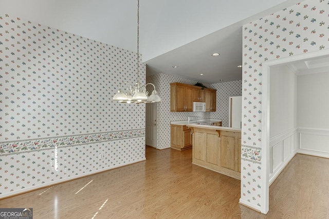 kitchen with wallpapered walls, light wood-style flooring, white microwave, light countertops, and stove