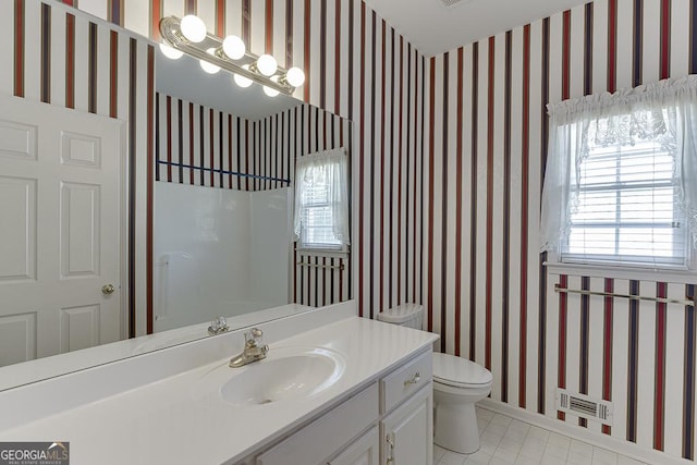 bathroom with wallpapered walls, toilet, vanity, and tile patterned flooring
