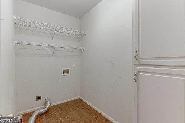 clothes washing area with electric dryer hookup, washer hookup, wood finished floors, and baseboards