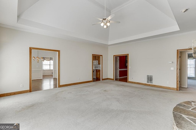unfurnished living room featuring carpet floors, a raised ceiling, ceiling fan, baseboards, and ornamental molding
