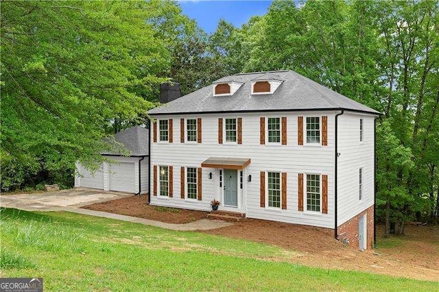 view of front of house featuring a chimney, a front yard, and a garage