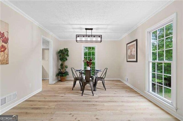 dining room featuring light wood finished floors, plenty of natural light, visible vents, and a textured ceiling