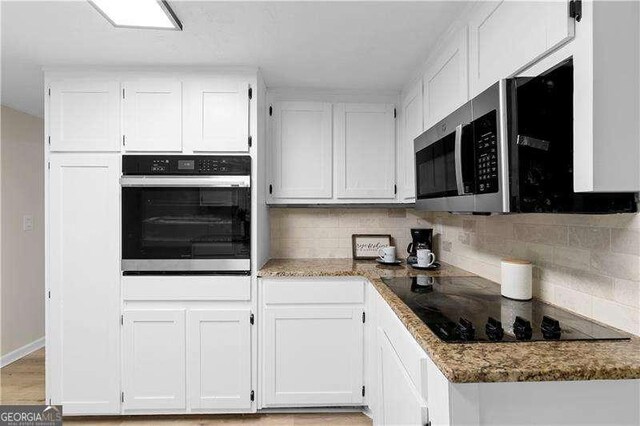 kitchen featuring white cabinets, stainless steel appliances, stone counters, and decorative backsplash