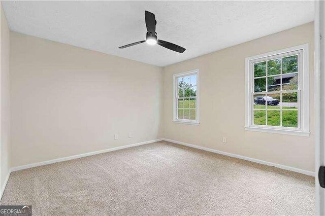 carpeted spare room with baseboards and ceiling fan