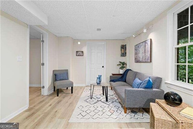 living area featuring baseboards, visible vents, and light wood finished floors