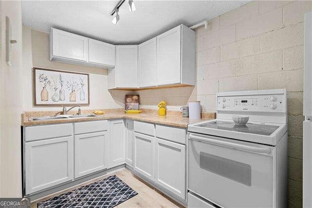 kitchen with a sink, light wood finished floors, light countertops, electric range, and white cabinets