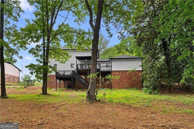 rear view of property featuring brick siding, stairs, and a deck