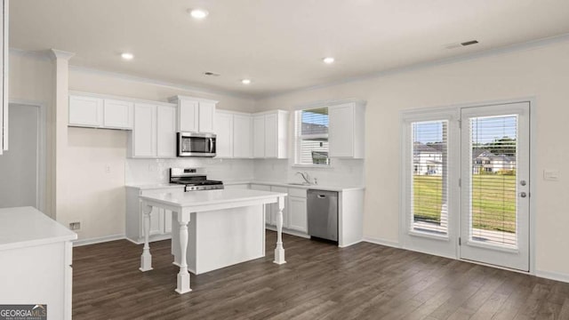 1109 Blue Juniper Cir, Loganville, GA 30052 - kitchen featuring appliances with stainless steel finishes, dark wood-style flooring, white cabinets, tasteful backsplash, and crown molding