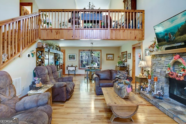 living room featuring stairway, a stone fireplace, visible vents, and wood finished floors
