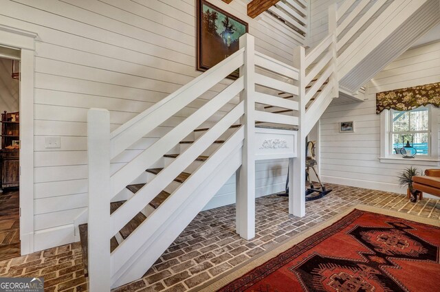 stairs featuring brick floor and wood walls