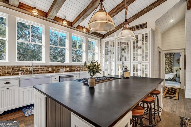 kitchen with lofted ceiling with beams, wood ceiling, stainless steel appliances, dark wood-style flooring, and a sink