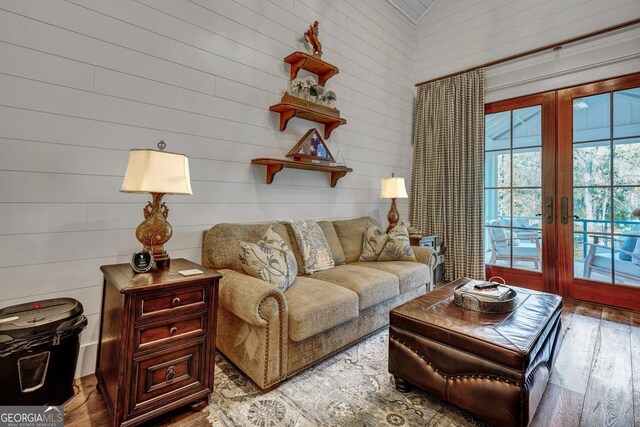 living area with wooden walls, wood finished floors, and french doors