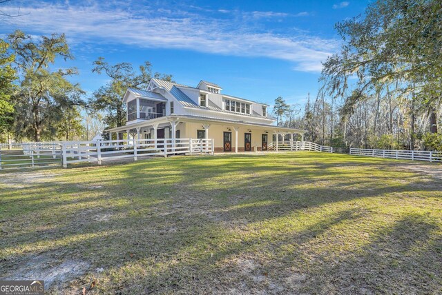 view of side of property featuring a yard, a fenced backyard, metal roof, and a sunroom