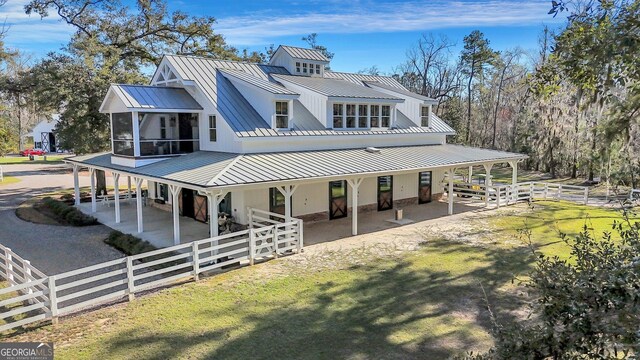 rear view of house featuring metal roof, a sunroom, an exterior structure, and a standing seam roof