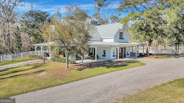 country-style home featuring fence, a front yard, and metal roof