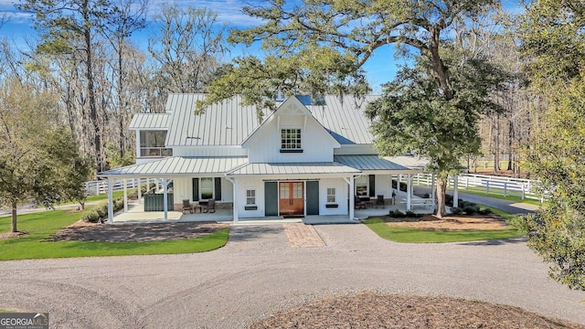 view of front of house with covered porch, a standing seam roof, fence, and dirt driveway