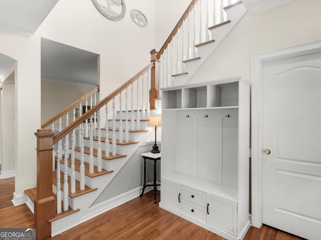 stairway with wood finished floors, baseboards, and arched walkways