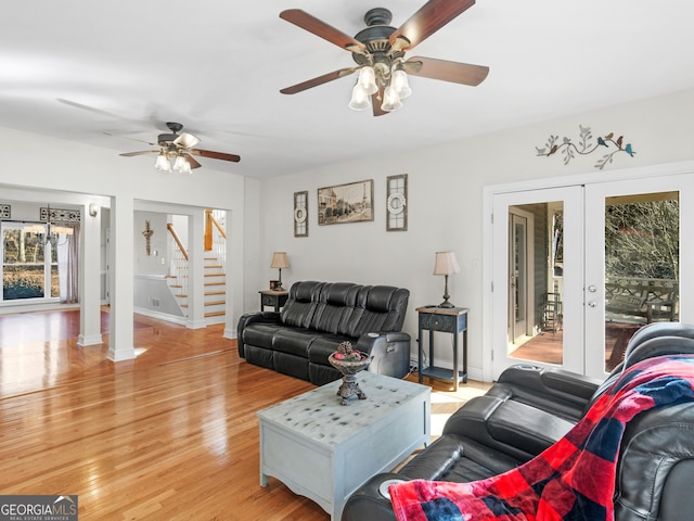 living room with ceiling fan, stairs, light wood-type flooring, baseboards, and french doors