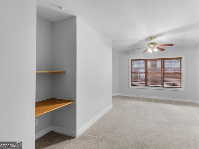 carpeted spare room featuring a ceiling fan and baseboards