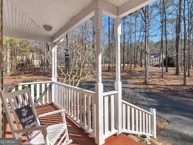 deck with a porch and view of wooded area