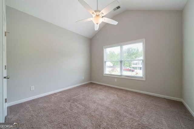 carpeted empty room with vaulted ceiling, a ceiling fan, and baseboards