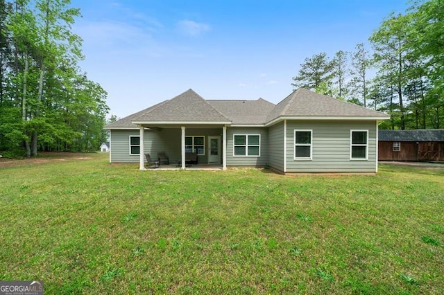 back of property featuring a patio area, a lawn, and a shingled roof