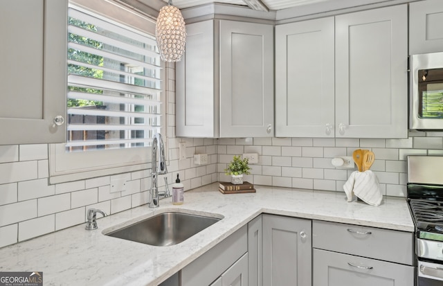 285 Lakemoore Dr NE Unit A, Atlanta, GA 30342 - kitchen featuring light stone counters, a sink, decorative backsplash, pendant lighting, and gray cabinetry
