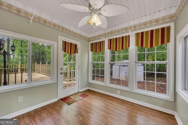 unfurnished sunroom with baseboards, wood finished floors, and plenty of natural light