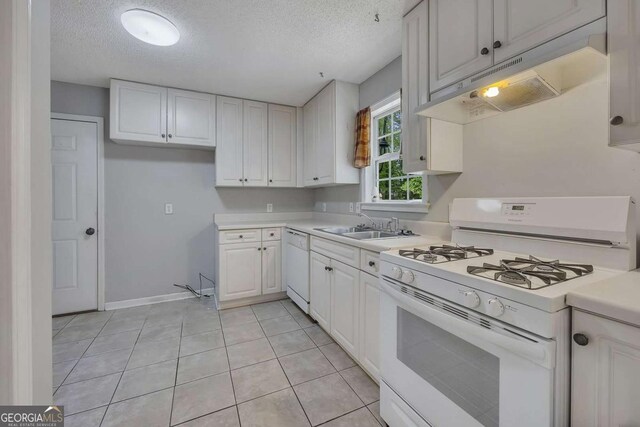 kitchen with light countertops, a textured ceiling, under cabinet range hood, and white appliances
