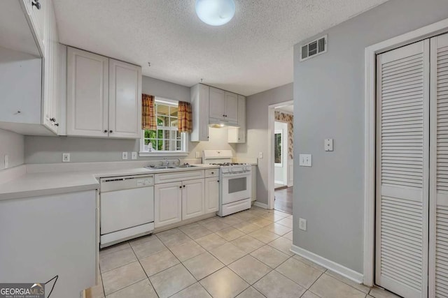 kitchen featuring a sink, a textured ceiling, visible vents, white appliances, and light countertops