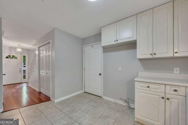 interior space with light countertops, a textured ceiling, white cabinetry, and light tile patterned floors