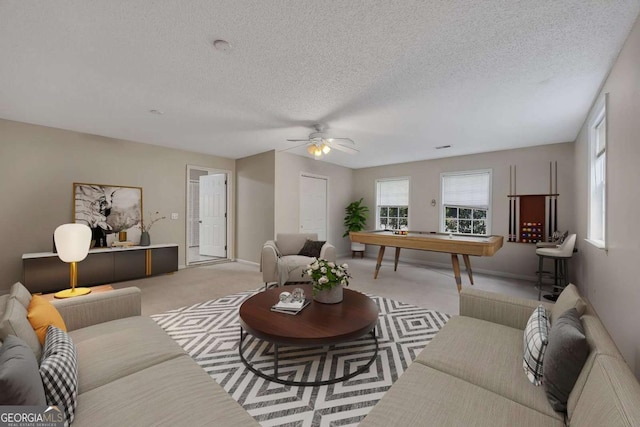 living area with carpet floors, a textured ceiling, a ceiling fan, and plenty of natural light