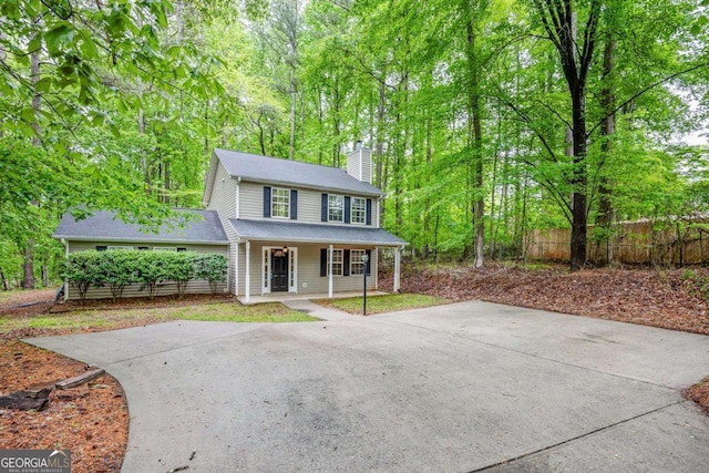 view of front of home with a chimney, fence, and a porch