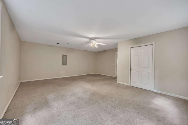 empty room with electric panel, baseboards, carpet, and ceiling fan