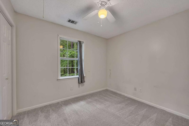 empty room featuring carpet floors, a textured ceiling, visible vents, and baseboards