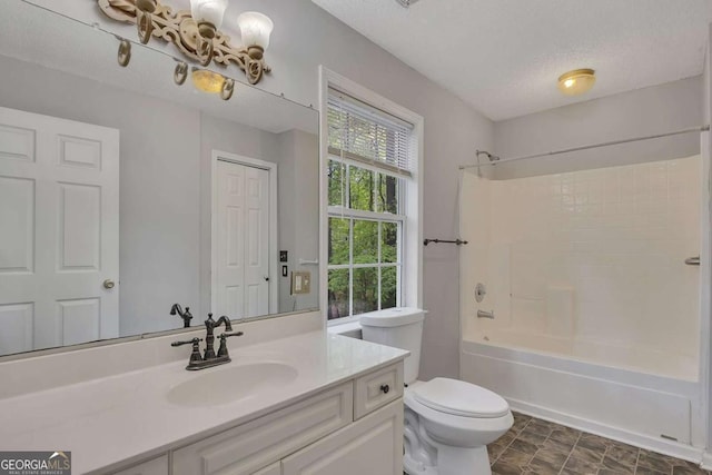 bathroom featuring toilet, vanity, a textured ceiling, and shower / bath combination
