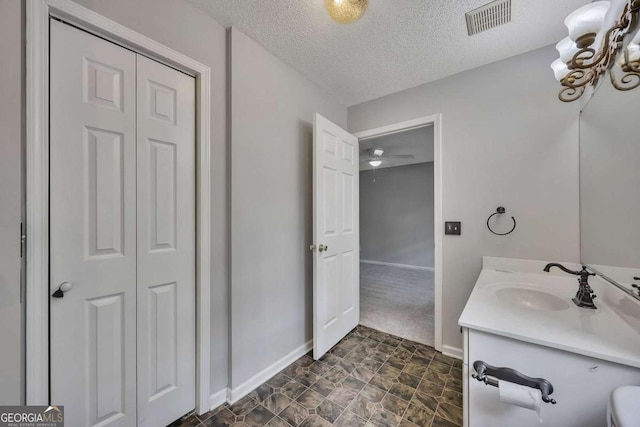 bathroom featuring visible vents, baseboards, a textured ceiling, and vanity