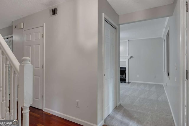 hall with a textured ceiling, visible vents, and baseboards