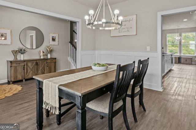 dining room with an inviting chandelier, a wainscoted wall, wood finished floors, and stairs