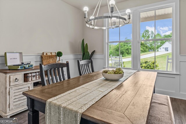 dining space with a decorative wall, a wainscoted wall, a chandelier, and dark wood finished floors