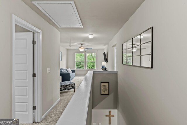 hall featuring attic access, baseboards, and carpet floors
