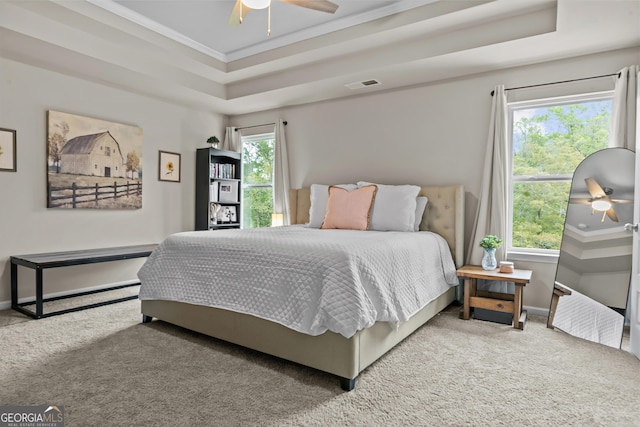 bedroom with crown molding, a raised ceiling, baseboards, carpet flooring, and visible vents
