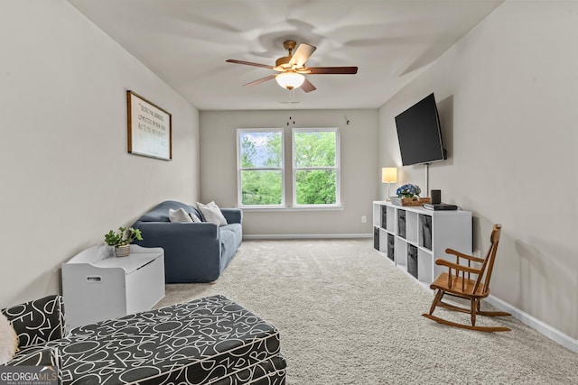carpeted living area featuring ceiling fan and baseboards