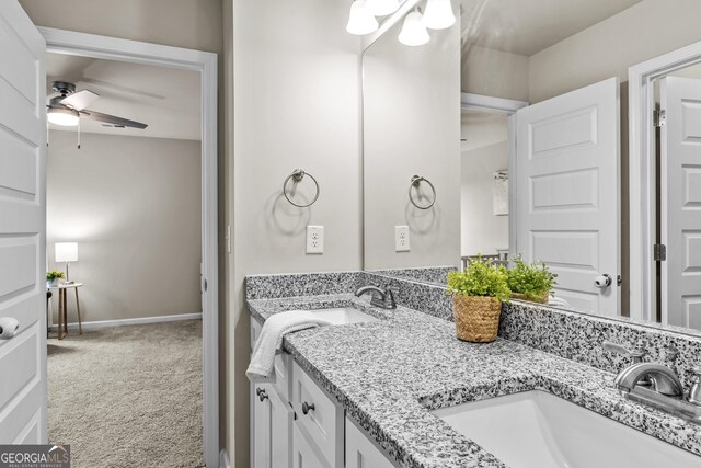 bathroom featuring a ceiling fan, baseboards, a sink, and double vanity
