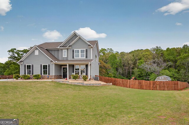 craftsman inspired home with central AC unit, fence, board and batten siding, covered porch, and a front yard